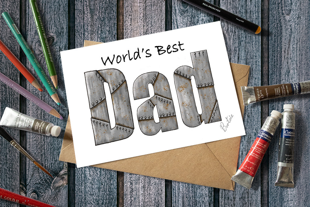 Card with 'World's Best Dad' text on a wooden surface with art supplies.